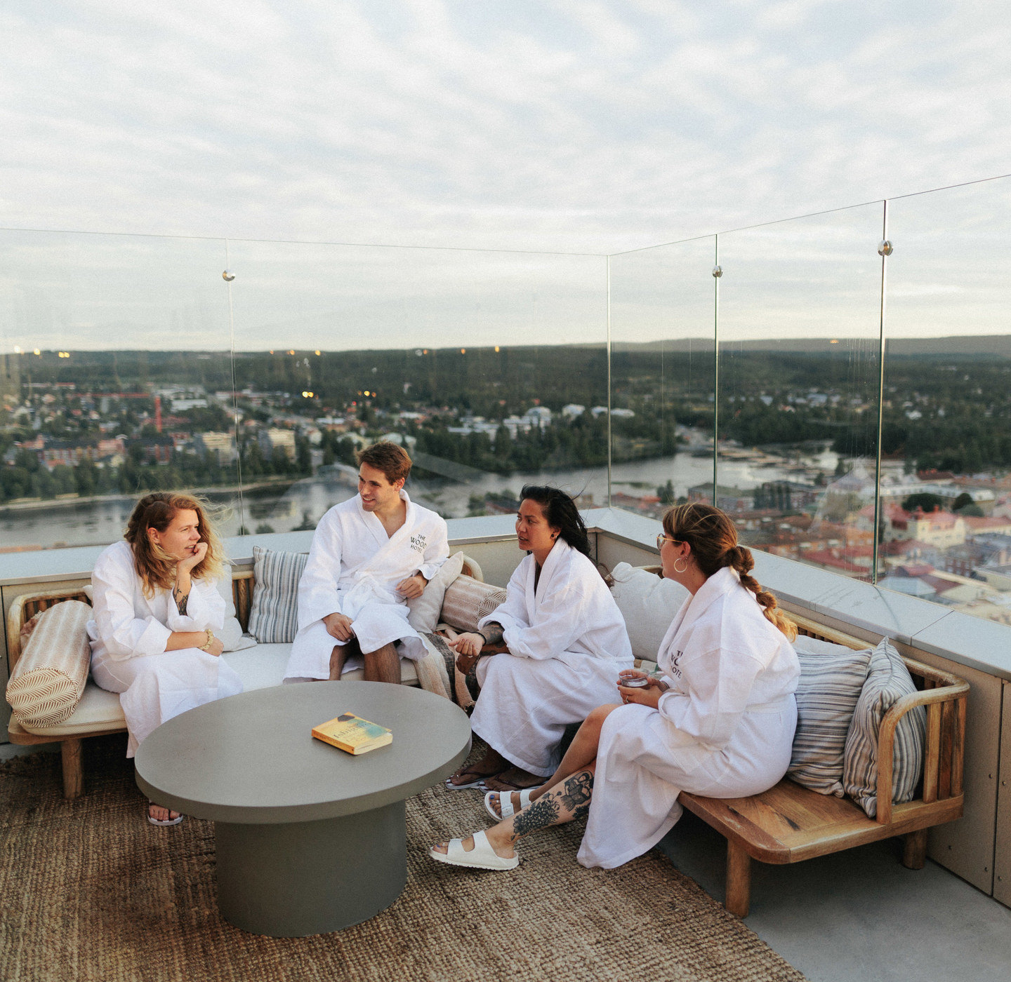 Four people in spa bathrobes are sitting on a roof top.  