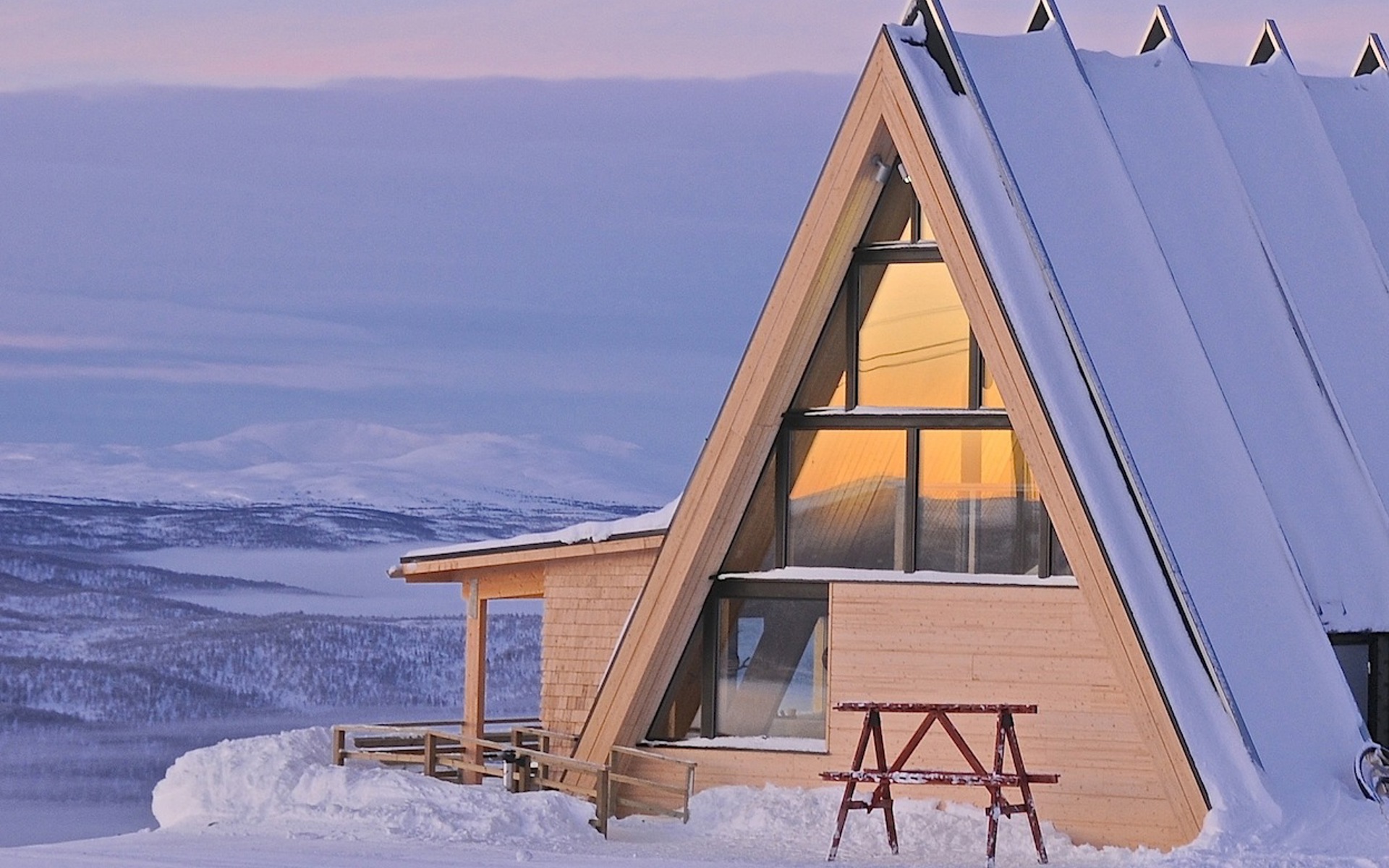 A building covered in snow, with snowy mountains in the background. 