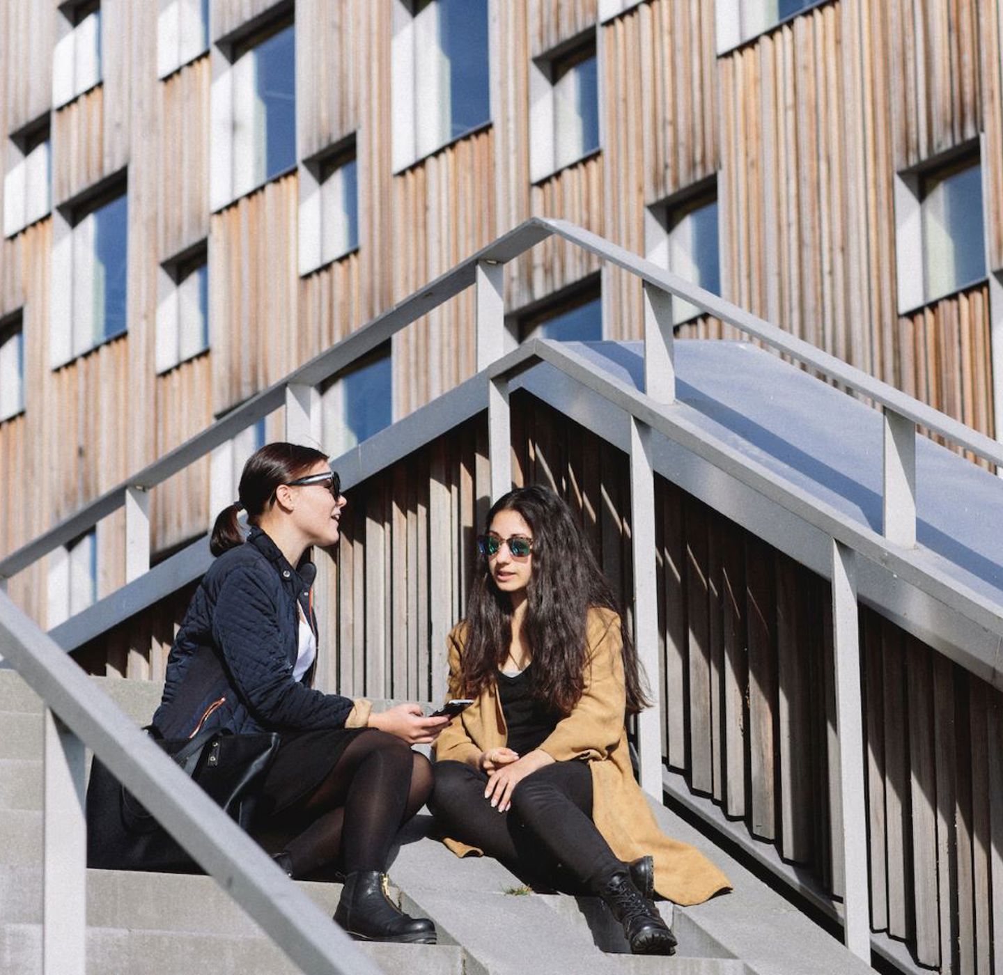 Two women sitting on a stair soaking up the sun. 